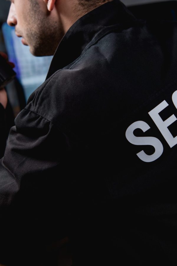 cropped view of guard in uniform holding walkie-talkie
