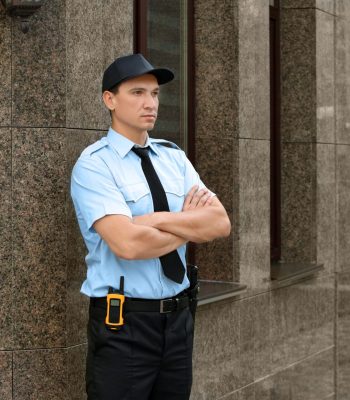 Male security guard near building, outdoors